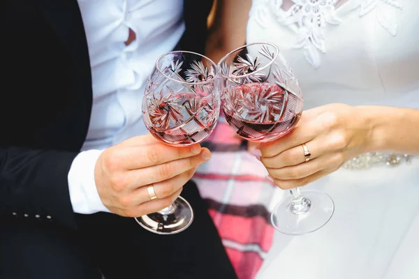 Dwa kieliszki wina w ręce nowożeńcy. Para jest sakiewkach brzęczały boczny. — Zdjęcie stockowe