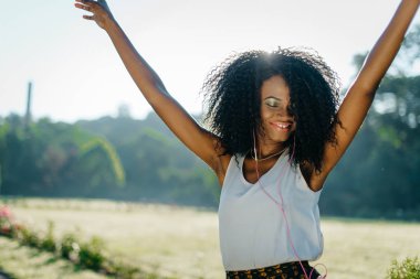 Yeşil göz gölgeler ve dans ve müzik kulaklık keyfi gülümsemek güzel etkin Afrikalı kız açık güneşli portresi.