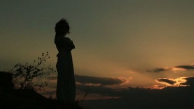 Rüzgar saç ve elbise karanlık ve altın güneşin tadını hareketli kadın silüeti.