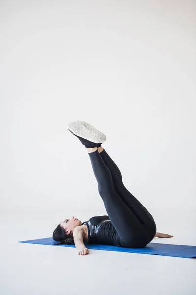 Foto tutorial untuk pemula olahraga. Pelatih brunette atletik berbaring di atas tikar latihan dan melakukan putaran mundur . — Stok Foto