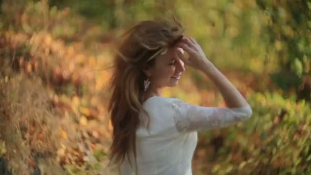 Portrait de la belle jeune brune souriante et corrigeant ses cheveux à cause du vent dans le parc doré .