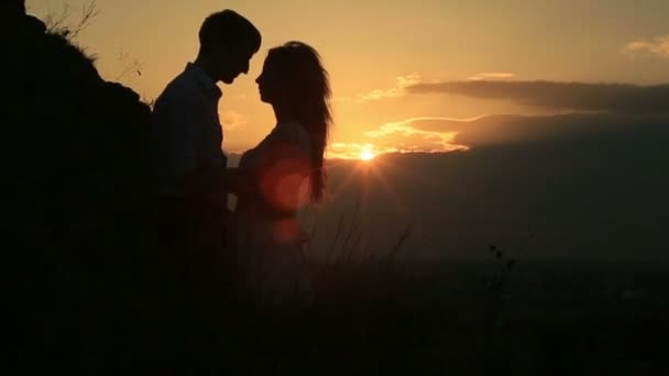Romantik Çift siluet şefkatle sarılma ve güzel altın gün batımı sırasında kafa kafaya ayakta bakış. — Stok video