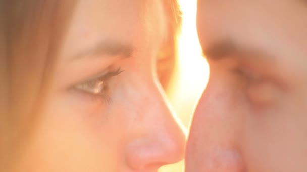 Close-up retrato sensível do jovem casal amoroso carinhosamente esfregando narizes no pôr do sol . — Vídeo de Stock