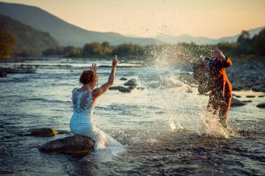 Neşeli sadece evli çift günbatımı sırasında birbirlerine su sıçramasına süre eğleniyor. Güzel manzara.