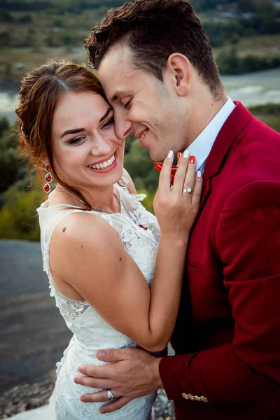 Känslomässiga porträtt av de glada nygifta leende och kramar utomhus. — Stockfoto