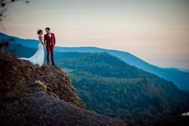 Romantik düğün atış. Büyüleyici yeni evliler dağ kenarında elele. Gün batımı sırasında güzel manzara.