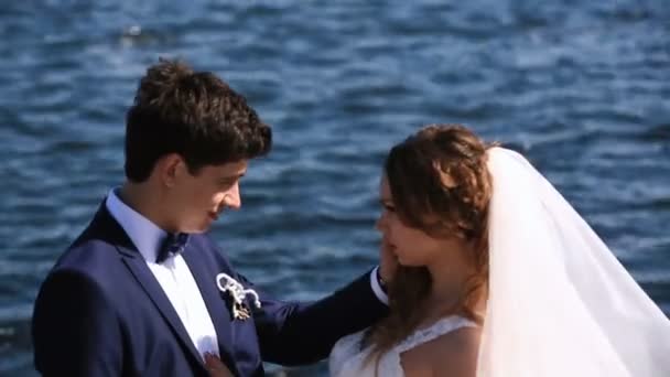 Жених целует привлекательную невесту на фоне моря . — стоковое видео