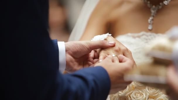 The groom is putting the wedding ring on the bride finger and kissing her hand. — Stock Video