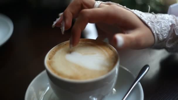La vue rapprochée du doigt de la mariée peignant le cœur sur le cappuccino .