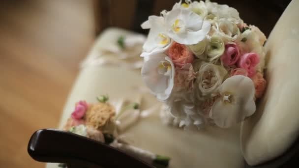 De två vackra bröllop buketterna av rosa och vita rosor och orkidéer ljuger på den antika vintage stolen. — Stockvideo