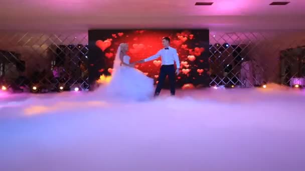 Bailando alegre hermosa pareja recién casada entre el humo grueso blanco en el fondo de la pantalla que muestra los corazones rojos. Ubicación del restaurante . — Vídeos de Stock