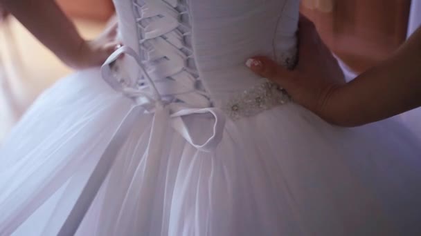 Le mani della damigella d'onore stanno legando l'arco e corresting l'abito da sposa elegante. Buongiorno della sposa. Vista posteriore. Senza volto . — Video Stock