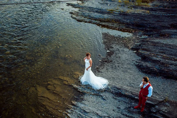 Над открытым свадебным портретом красивых молодоженов, смотрящих друг на друга, стоя на берегу реки . — стоковое фото