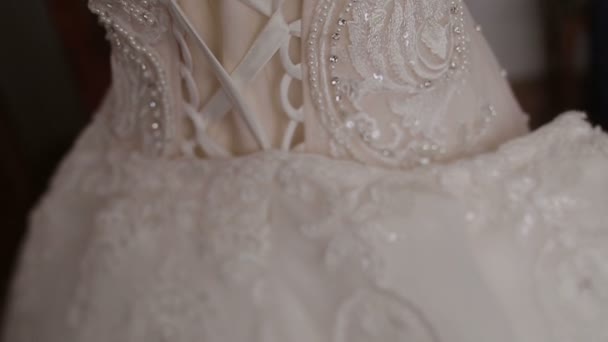 The back view of the rich wedding dress with corset and sparkles hanging on the vintage mannequin. — Stock Video