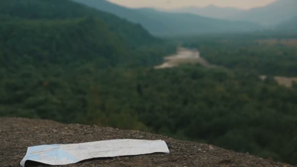 The close-up view from drone on the map laying on the mountains at the background of the beautiful landscape of the river and forest. — Stock Video