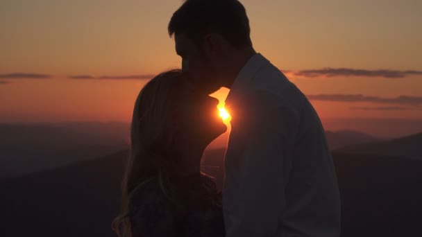 Όμορφος άντρας είναι φιλώντας την ερωμένη του στο μέτωπο και τα χείλη με φόντο το ηλιοβασίλεμα. — Αρχείο Βίντεο