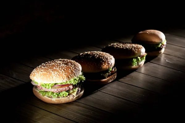 Świeże, smaczne Burgery z rzędu. Burgery, umieszczone na drewnianym stole. — Zdjęcie stockowe