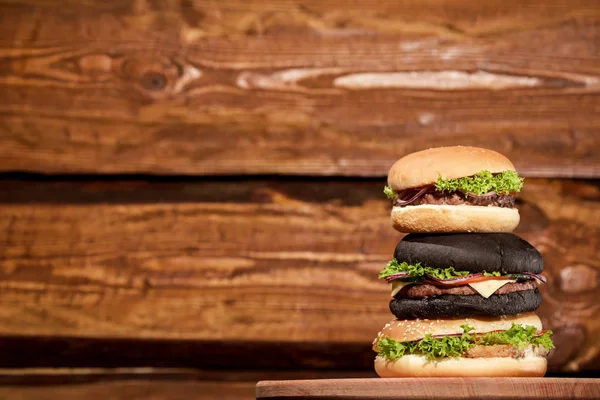 Płci i wieku: trzy świeże mięso Burgery umieszczone na tle drewnianych. — Zdjęcie stockowe
