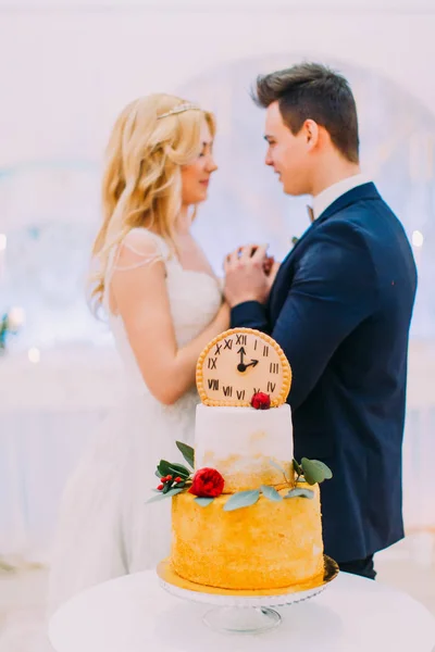 Wedding couple lovingly look at each other. Sweet cake on foreground