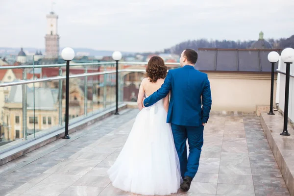 Die Rückansicht des wandelnden Brautpaares auf dem Dach. — Stockfoto