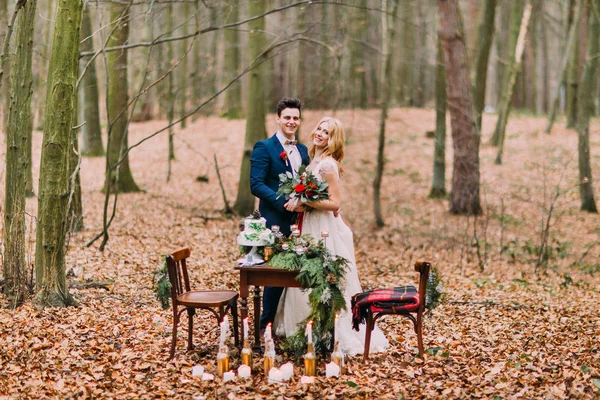 Красива весільна пара позує біля старовинного столу в осінньому лісі — стокове фото
