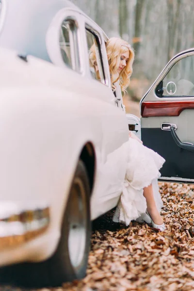 Linda noiva loira em carro vintage branco. Floresta de outono no fundo — Fotografia de Stock