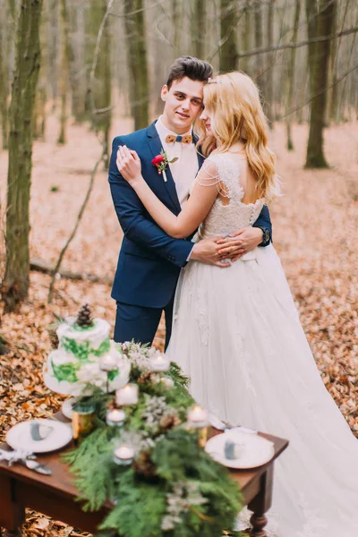 Beau couple de mariage posant près de la table vintage dans la forêt d'automne — Photo