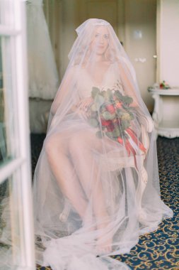 Seksi sarışın gelin buketi tutan peçe ve beyaz iç çamaşırınla giyinmiş