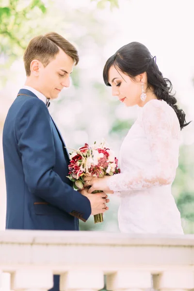 O retrato de meio comprimento dos recém-casados segurando o colorido buquê de casamento . — Fotografia de Stock