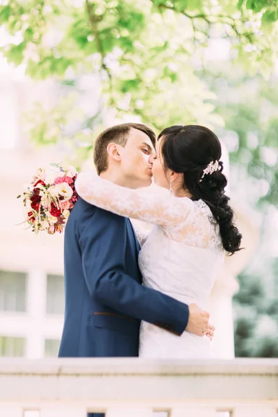 El retrato al aire libre lateral de los recién casados besándose . — Foto de Stock