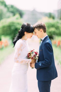 Düğün vouquet kafa kafaya ayakta iken holding yeni evli çift yakın çekim yan portresi.