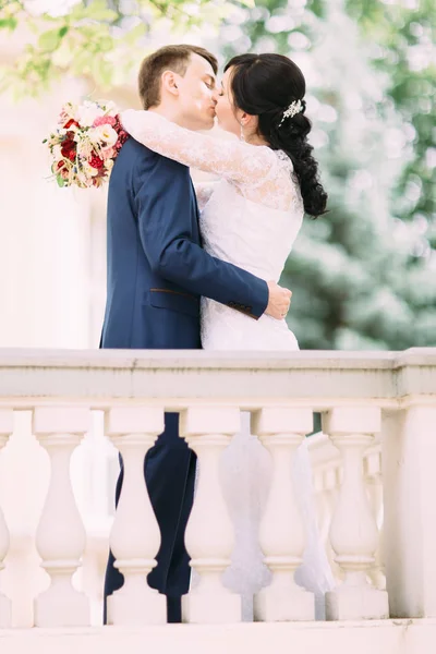 Le portrait extérieur complet du couple de jeunes mariés qui s'embrassent . — Photo