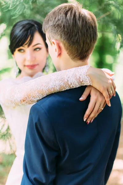 De achterkant van de bruidegom in focus. De bruid is de bruidegom knuffelen. — Stockfoto