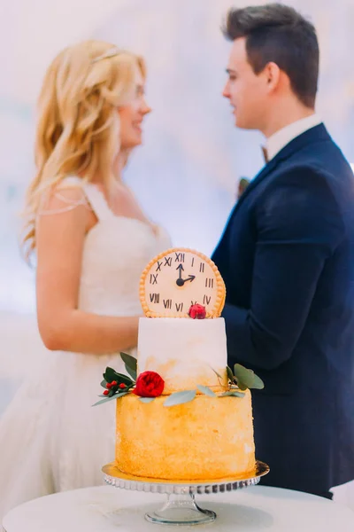 Casamento casal carinhosamente olhar um para o outro. Bolo doce em primeiro plano — Fotografia de Stock