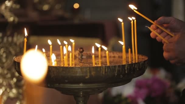 Frauenhände entzünden die Kerzen mit Hilfe einer anderen in der Kirche. — Stockvideo