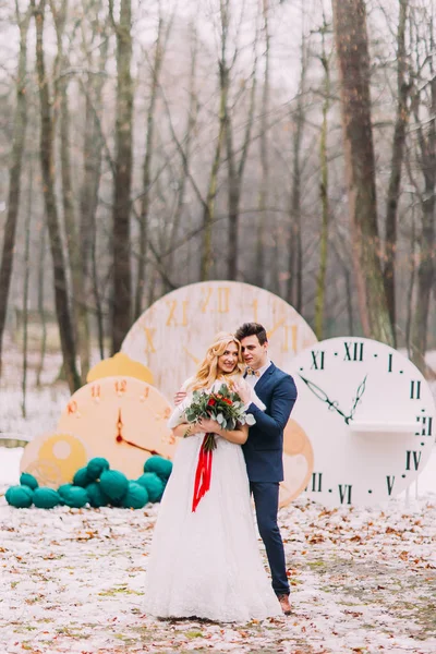 Casal feliz posando nos grandes relógios vintage na floresta de outono. Decorações criativas — Fotografia de Stock