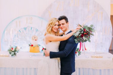 Güzel sarışın gelin ve damat usulca restoranda gül buketi ile sarılmak. 