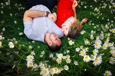 Her diğer ve çiçek papatya çayır üzerinde döşeme üzerinde gülümseyen güzel çiftin yakın çekim portre bakarak.
