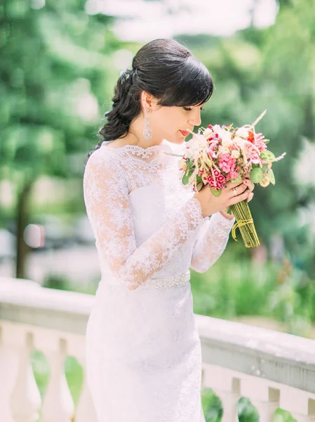 Il ritratto laterale della bella sposa che annusa il bouquet da sposa . — Foto Stock