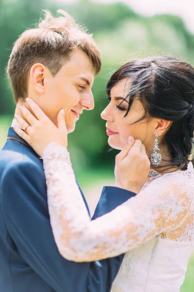 Le couple de jeunes mariés se caresse les joues. Le portrait latéral en gros plan . — Photo