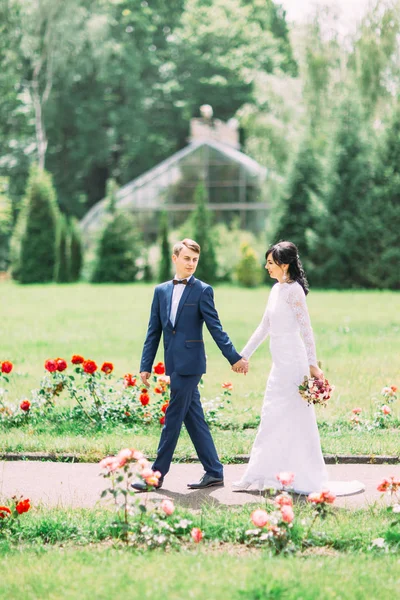 Fröhlicher Spaziergang des fröhlichen Brautpaares im Park. — Stockfoto