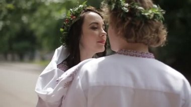 Güzel çift çiçek çelenk ve şefkatle burun sürtme nakış kumaş hassas oudoor portresi. Çekici kız sevgilisini boynundan öpüyor.