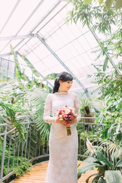 Retrato de meio-comprimento da noiva olhando para o lado e rodeado por diferentes plantas . — Fotografia de Stock