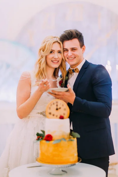 Novio guapo alimentando a su hermosa novia rubia con pastel de boda — Foto de Stock