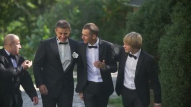 Düğün kavramı. Genç yakışıklı damat mutlu Bahçe yürürken üç sağdıcı ile konuşuyor.