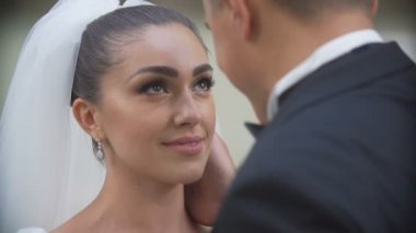 Damat şefkatle gülümseyen güzel gelini kafasından öpüşme hassas portresi. Omzunun üzerinden görüntüleyin. Yakın çekim.