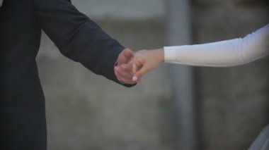 Yeni evli çiftin yakın çekim shot şefkatle elele geziyor. Damat gelin el usulca öpüşme.