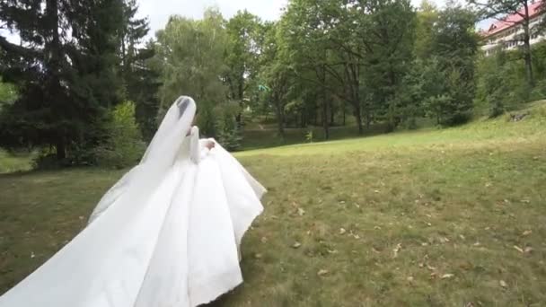 Vue complète de la belle mariée brune qui longe le jardin en robe de mariée longue . — Video