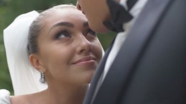 Damat güzel gülümseyen gelin kafasından öpüyor. Çekici esmer onun sho ulder yaslanmış ve onun gözlerine bakmak.