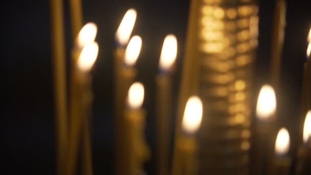 Αναμμένα κεριά στην εκκλησία στο μαύρο φόντο. Άναψε τα κεριά. Προβολή με μεγέθυνση. — Αρχείο Βίντεο